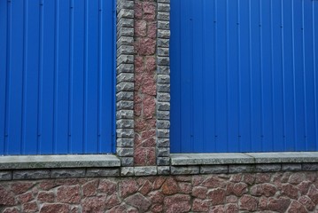  texture of blue metal and gray bricks in the wall of the fence