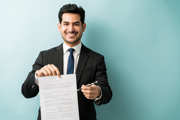 Businessman Offering Pen And Agreement At Studio