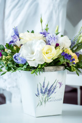 A tender bouquet of flowers in a bucket on a white chair in the bedroom.