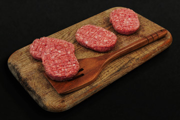 Fresh raw pork or beef meatballs on old rustic wooden cutting board background. Soft and selective focus.
