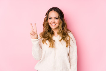 Young curvy woman posing in a pink background isolated showing number two with fingers.