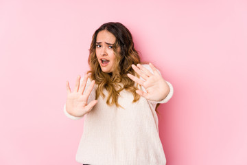 Young curvy woman posing in a pink background isolated being shocked due to an imminent danger