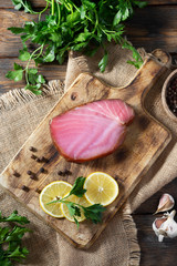 Smoked tuna on a wooden Board on a brown wooden table. Top view with space for text	