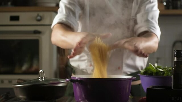 cook throws spaghetti into pot of boiling water. Preparation of ingredients by male chef to prepare noodles for pasta. Cooking in restaurant kitchen. Modern cooking. Food ingredients for gourmets