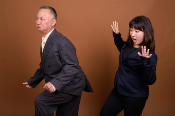 Mature Asian businessman farting at mature Asian businesswoman