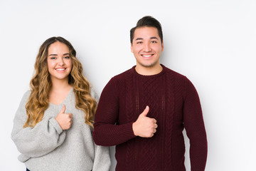 Young couple posing in a white background smiling and raising thumb up