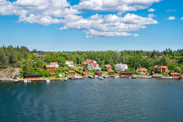 Cozy Scandinavian cottages located on the coastline of the archipelago in Sweden. Colorful summer landscape with houses on the shore of the Baltic Sea.