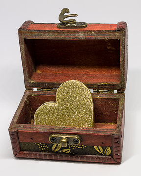 Cofre retro de color marr&oacute;n oscuro con cierre de lat&oacute;n y decorado con detalles en lat&oacute;n y un gran coraz&oacute;n dorado en su interior.