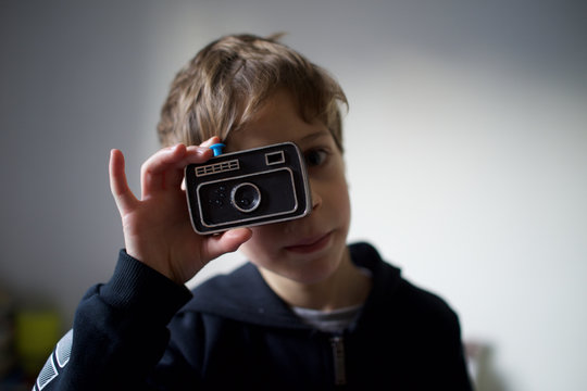 Little boy with a trick, joke, toy - water squirting, plastic camera - pretending to take a photo