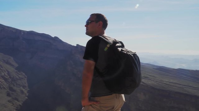 Young Foreign Male Tourist Enjoying the View of Wadi Ghul aka Grand Canyon of Oman in Jebel Shams Mountains. Man in Active Solo Travel in Middle East Countries