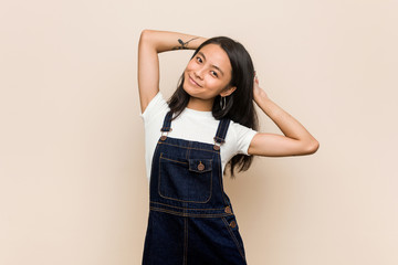 Young cute chinese teenager Young blonde woman wearing a coat against a pink background stretching arms, relaxed position.
