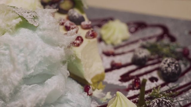 A cheesecake with berries is taken with a dessert spoon on a plate. close-up