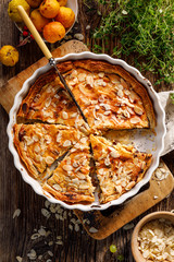 Cheese and poppy seed tart, sweet tart sprinkled with almonds flakes on a wooden rustic table, top view.  A delicious homemade dessert 