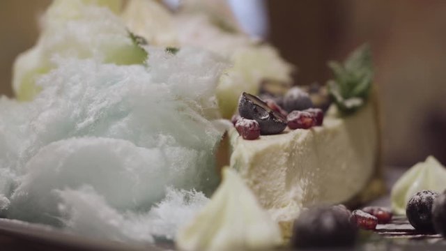 A cheesecake with berries is taken with a dessert spoon on a plate. close-up