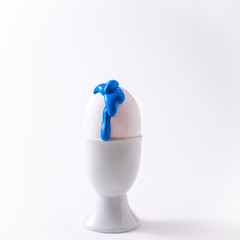 Easter egg with liquid paint on it. Minimalism concept. Classic blue colour trend on white background