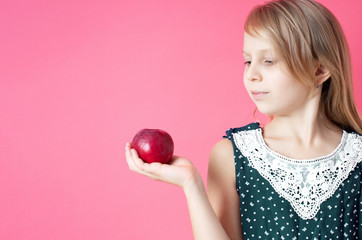 Portrait of happy girl with red apple isolated on pink background