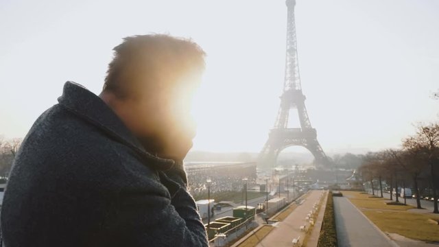 Happy professional photographer man taking a backlit picture of Eiffel Tower in Paris with vintage camera slow motion.