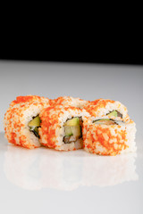 delicious California roll with avocado, salmon and masago caviar on white surface isolated on black