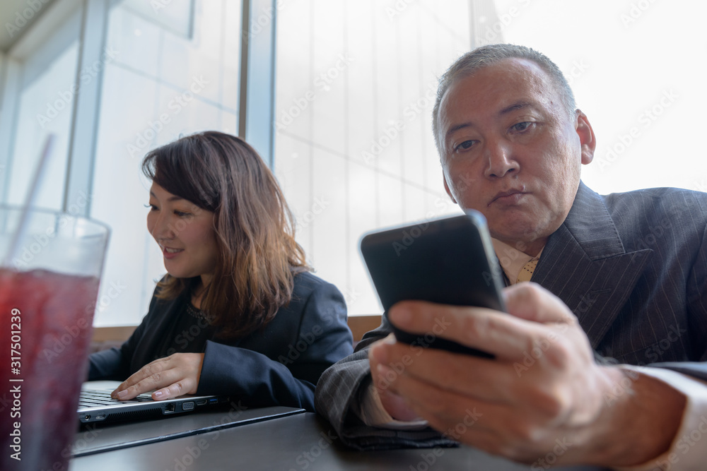 Wall mural mature asian businessman and mature asian businesswoman working at restaurant together