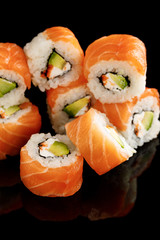 delicious Philadelphia sushi with avocado, creamy cheese, salmon and masago caviar isolated on black