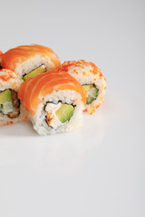 close up view of delicious Philadelphia and California sushi with salmon and masago caviar on white background