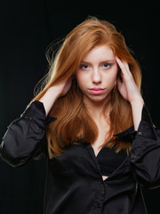 Fototapeta premium young girl with long red hair on a black background
