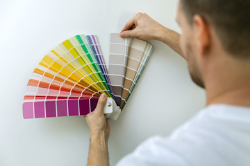 man selecting paint color from swatch for room wall