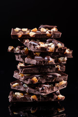 Stack of Broken Chocolate Pieces on Black Background. Copy Space. Closeup View