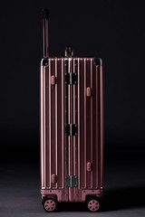 Delicate rose gold suitcase on black background