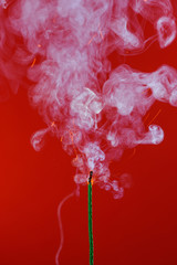 Burning fuse wick with sparks and smoke on red background