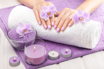 Obraz na płótnie Canvas beautiful pink manicure with decor, orchid, towel and candle on the white wooden table. spa