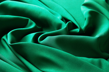 Green emerald color silk fabric background, top view.