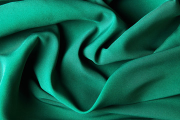 Green emerald color silk fabric background, top view.