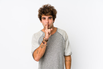 Young caucasian man against a white background isolated keeping a secret or asking for silence.