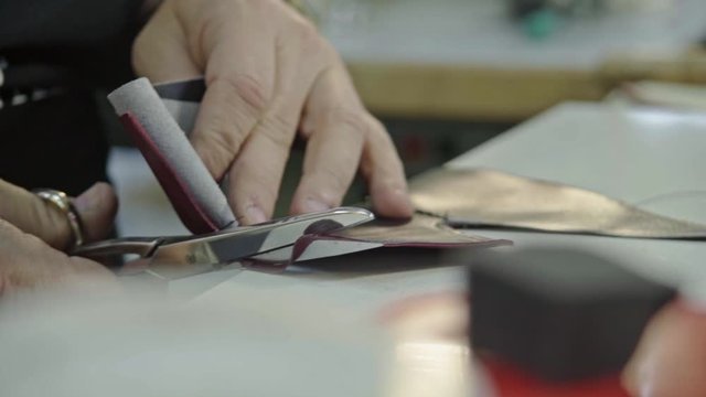 Craftsman gluing and stiching all parts of a upper part of a shoe together. 