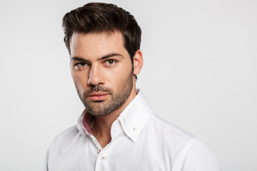 Image of young caucasian businessman posing and looking at camera