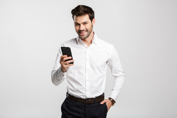 Image of happy successful businessman typing on cellphone and smiling