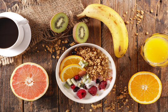 muesli with yogurt and fruit, orange juice and coffee cup