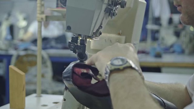 Craftsman gluing and stiching all parts of a upper part of a shoe together. 