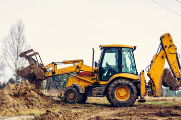 The excavator in the countryside moves the concrete slabs for the road.