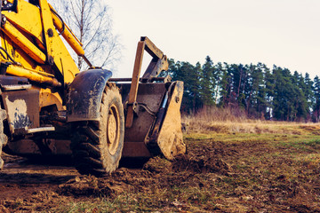 Grader clearing and leveling of the soil to install concrete slabs.