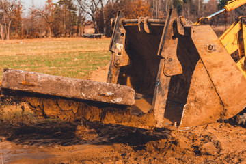 The yellow excavator transports concrete slabs in the countryside.