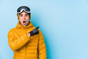 Young skier man wearing snowboard goggles isolated pointing to the side