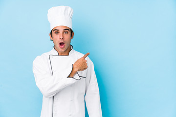 Young cook man isolated pointing to the side