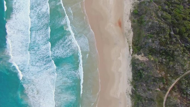 High angle aerial bird's eye drone footage of famous Seventy Five Mile Beach on Fraser Island, Queensland, Australia. The Island is popular for tourist with four-wheel drive vehicles.