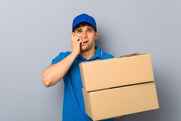 Young man delivering packages biting fingernails, nervous and very anxious.