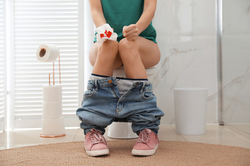 Woman holding toilet paper with blood stain in rest room, closeup. Hemorrhoid concept
