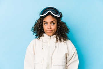 Young african american skier woman isolated confused, feels doubtful and unsure.