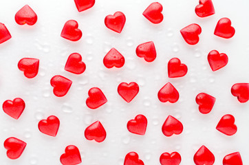 white background with red hearts pattern and water drops, flat lay