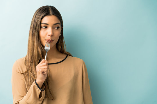 Hispanic Woman Enjoying Food Over Blue Background